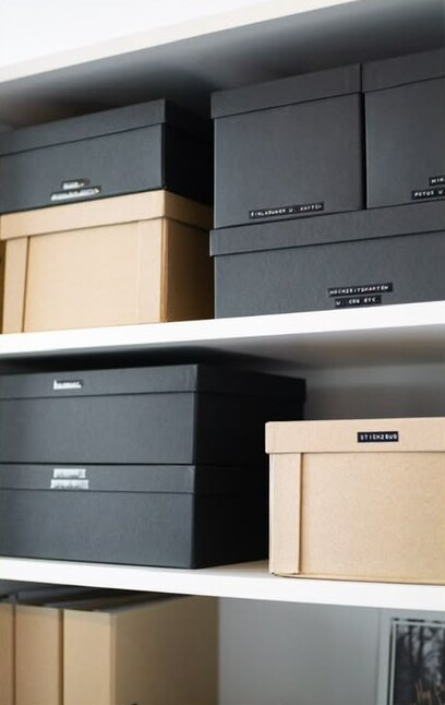 Beschriftete Aufbewahrungsboxen in Schwarz und Kraftpapier
