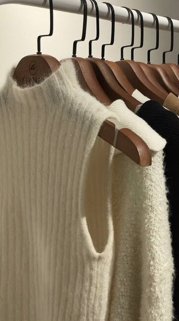 Strickpullover auf Holzbügeln in einer aufgeräumten Garderobe